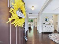 Inviting foyer with hardwood floors, an elegant console table, and a yellow floral wreath on the front door at 1701 Bodwin Ln, Apex, NC 27502