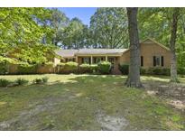 Charming single-story brick home surrounded by lush greenery and a well-maintained lawn at 2001 Lovdal Dr, Raleigh, NC 27613