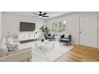 Bright living room with a ceiling fan, accent chairs, and modern decor at 2311 Wintergreen Pl, Durham, NC 27707