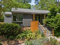Charming home featuring stylish wood accents, gray siding, and beautifully landscaped front yard at 2529 Remington Rd, Raleigh, NC 27610