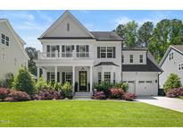 Charming two-story white home featuring a welcoming front porch and well-manicured lawn at 2993 Club Dr, Raleigh, NC 27613