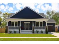 Charming navy home featuring a covered porch, white trim, and well-manicured landscaping at 305 W Waddell St, Selma, NC 27576