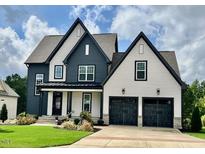 Charming two-story home with a two-car garage, manicured lawn, and beautiful blue and white color scheme at 324 Prides Xing, Rolesville, NC 27571