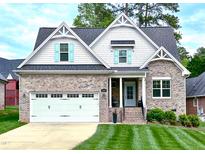 Charming brick home with manicured lawn, two-car garage, and inviting front entrance at 409 Eagle Ct, Henderson, NC 27536