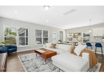 Bright living room featuring a white sectional sofa, wood floors, and natural light at 5009 Megara Run, Raleigh, NC 27603