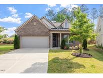 Charming brick home featuring an attached garage and a beautifully landscaped front yard with lush green grass at 52 Brunello Ct, Clayton, NC 27527