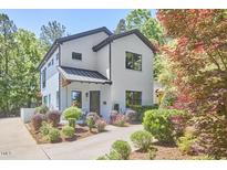 Charming renovated two-story home with white brick, black trim, manicured landscaping, and covered front porch at 631 Linfield Dr, Durham, NC 27701