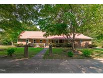 Charming brick home featuring a beautiful red roof, a welcoming porch, and mature trees in the front yard at 9108 Ransdell Rd, Raleigh, NC 27603