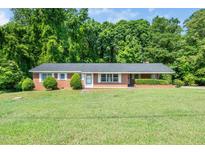 Charming single-story brick home featuring a well-manicured lawn and mature trees at 1041 Davis Dr, Apex, NC 27523