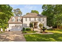 Stunning white brick home featuring a circular balcony, water fountain, lush landscaping and a three-car garage at 106 Clendenen Ct, Cary, NC 27513