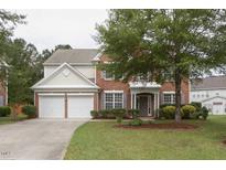 Charming two-story brick home featuring an attached two-car garage and a well-manicured lawn with mature trees at 110 Bristolwood Cir, Morrisville, NC 27560