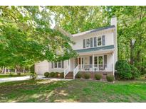 Charming two-story home with a welcoming front porch, lush landscaping, and attached garage at 110 Ferris Wheel Ct, Cary, NC 27513