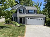 Charming two-story home with a well-manicured lawn and a two-car garage, nestled amidst lush greenery at 1208 Olympic Dr, Mebane, NC 27302