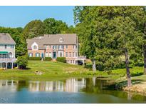 Stunning brick home with lush lawn, surrounded by trees and a serene lake view at 12527 Bellstone Ln, Raleigh, NC 27614