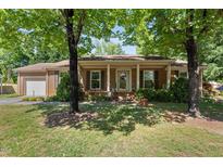Charming brick home with a covered porch, mature trees, and well-maintained landscaping at 1612 Regency Dr, Burlington, NC 27215