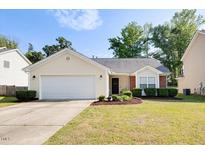 Well-maintained home featuring a two-car garage, manicured lawn, and charming front garden at 1826 Heisser Ln, Fuquay Varina, NC 27526