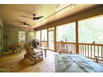 Covered outdoor patio with ceiling fans, brick accents, and wood furniture for relaxing and entertaining at 197 W Paige Wynd Dr, Angier, NC 27501