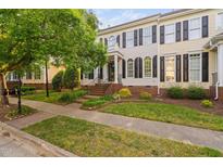 Charming townhouse with brick foundation, landscaped lawn, black shutters, and a tree-lined sidewalk at 210 Presidents Walk Ln, Cary, NC 27519