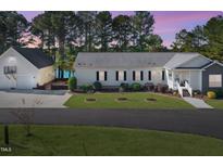 Charming home featuring an attached garage and a well-manicured front yard with a lake view, perfect for peaceful living at 215 Collins Rd, Lillington, NC 27546
