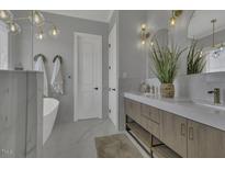 Stylish bathroom showcasing a luxurious soaking tub, double vanity with marble counters, and elegant lighting fixtures at 25 Westbourne Ln, Youngsville, NC 27596