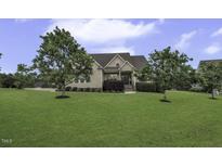 Charming two-story home featuring a well-manicured lawn, mature trees, and welcoming front porch at 25 Westbourne Ln, Youngsville, NC 27596