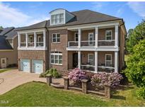 Stunning two-story brick home featuring double balconies, lush landscaping, and a two-car garage at 2820 Charleston Oaks Dr, Raleigh, NC 27614