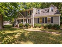 Charming two-story home with grey siding, black shutters, a well-manicured lawn and mature trees at 3113 Chelmshire Ct, Raleigh, NC 27610