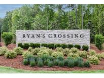 Stone entrance sign for Ryan's Crossing with beautiful landscaping and a natural, wooded backdrop at 480 Lila Dr, Pittsboro, NC 27312