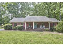 Charming single-story brick home with red shutters and a spacious front lawn with mature trees at 5319 Memory Ln, Durham, NC 27712