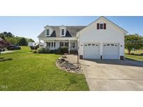 Charming two-story home with a manicured lawn, white siding, double garage, and welcoming front porch at 79 Blande Dr, Kenly, NC 27542