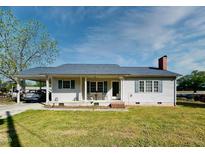 Charming single-story home featuring a carport, covered front porch, light siding and green shutters at 107 N Pearl St, Princeton, NC 27569