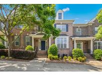 Charming brick townhouse with manicured landscaping, covered entrance, and a beautifully blue summer sky at 1103 Weston Green Loop, Cary, NC 27513