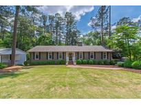 Charming single-story home with a manicured lawn, brick pathway, and lush green landscaping at 1305 Kimberly Dr, Raleigh, NC 27609
