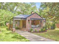 Charming brick home featuring a quaint front porch and well-maintained landscaping, inviting curb appeal at 1307 Arnette Ave, Durham, NC 27707