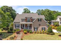 Charming two-story home with a welcoming front porch and beautifully landscaped front yard with mature trees at 1437 Chelton Oaks Pl, Raleigh, NC 27614