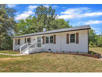Charming white home featuring a brick facade, decorative shutters, manicured landscaping, and inviting front porch at 1732 Green Pace Rd, Zebulon, NC 27597