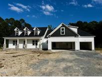 Charming new construction home with a three-car garage, white siding, and a welcoming front porch at 196 Cozy Brook Ct, Clayton, NC 27520