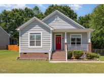 Charming home featuring a brick foundation, red front door, and a cozy front porch with white railing at 209 Mccarthy Dr, Clayton, NC 27527