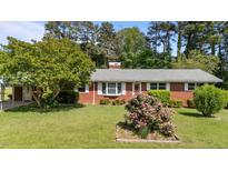 Charming brick home featuring a lush lawn and garden beds bursting with colorful flowers at 2910 Dove Ln, Raleigh, NC 27604