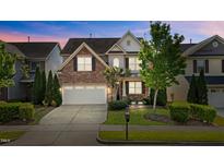 Charming home showcasing manicured lawn, brick accents, and a two-car garage at 309 Windy Peak Loop, Cary, NC 27519