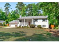 Charming white brick home with grey shutters, manicured lawn, and an American flag displayed at 4109 Huckleberry Dr, Raleigh, NC 27612