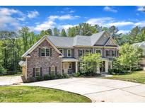 Beautiful two-story home with a stone and gray facade, a well-manicured lawn and plentiful driveway space at 7304 Hasentree Club Dr, Wake Forest, NC 27587