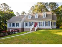 Charming two-story home featuring blue shutters, dormer windows, and a well-maintained lawn at 7405 Chickadee Ct, Sanford, NC 27332