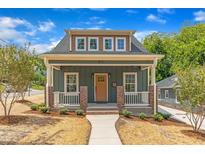 Charming green home featuring a welcoming front porch and well-manicured landscaping at 801 N Elm St, Durham, NC 27701