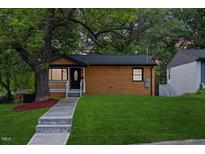 Charming home features a covered porch, wood siding, green lawn, and mature shade tree at 805 Camden Ave, Durham, NC 27701