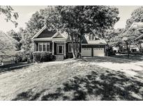 Charming brick home with a well-manicured lawn, mature trees, and two-car garage at 104 Crossway Ln, Holly Springs, NC 27540