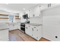 Well-lit kitchen with white cabinets, stainless steel appliances, marble countertops, and a farmhouse sink at 105 N 11Th St, Erwin, NC 28339