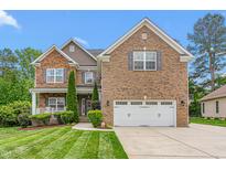 Beautiful brick two-story home with an attached two-car garage and manicured lawn at 114 Bell Tower Ct, Elon, NC 27244