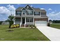 Traditional two-story home with stone accents, attached garage, and a well-manicured lawn at 11412 International Dr, Middlesex, NC 27557