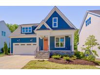 Charming two-story home featuring a blue exterior, stone accents, an orange front door and an attached garage at 127 Post Oak Rd, Chapel Hill, NC 27516